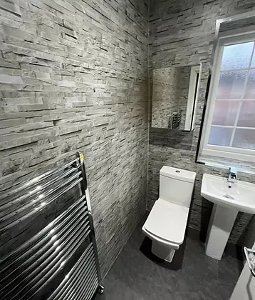 Open-plan wetroom with splitstone cladding, white furniture and grey tile-effect LVT flooring in Durham