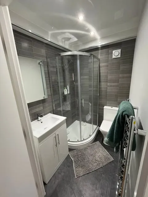 Freestanding bath with grey tile-effect walls and chrome fittings